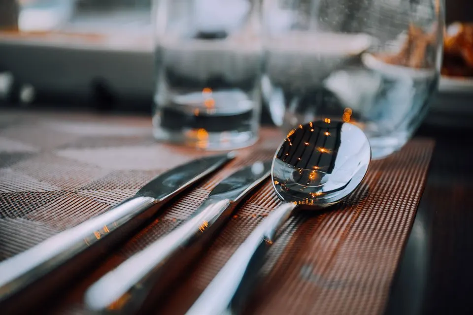 7132 Silver — A close-up shot of shiny silver cutlery on a table, reflecting warm lighting.