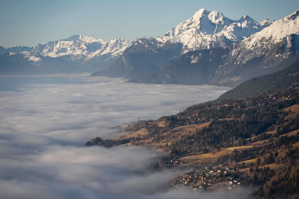 Chetzeron — Breathtaking view of the Swiss Alps with a sea of clouds enveloping Crans-Montana at sunrise.