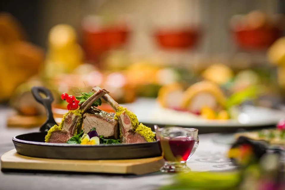 Culinarium Alpinum — Close-up of a gourmet lamb rack with herbs, served with sauce, on a rustic table setting. Perfect for…