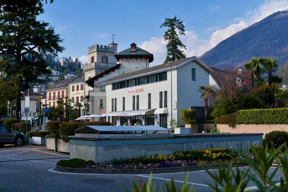 Ecco — Picturesque view of Locarno, Switzerland featuring historic architecture and vibrant flowers.