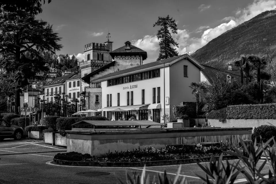 Ecco — Black and white view of historic buildings in Ascona, Switzerland featuring Osteria architecture.