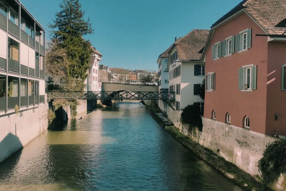 Scenic view of a river flowing through Frauenfeld, Switzerland, with historic buildings on both sides.