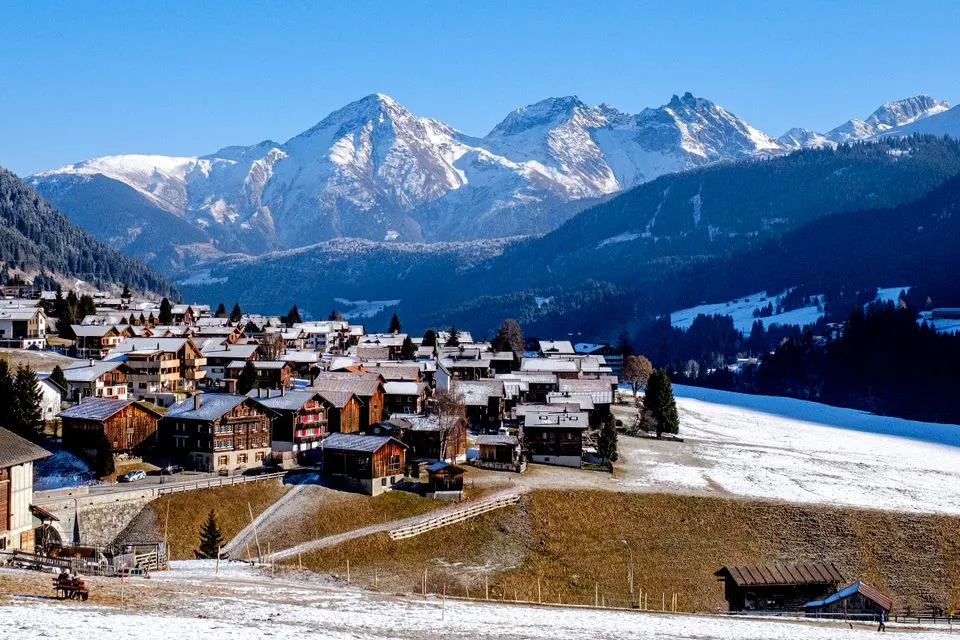Guarda Golf Hotel & Residences — Picturesque Swiss village nestled in snow-capped Alps with stunning winter scenery.