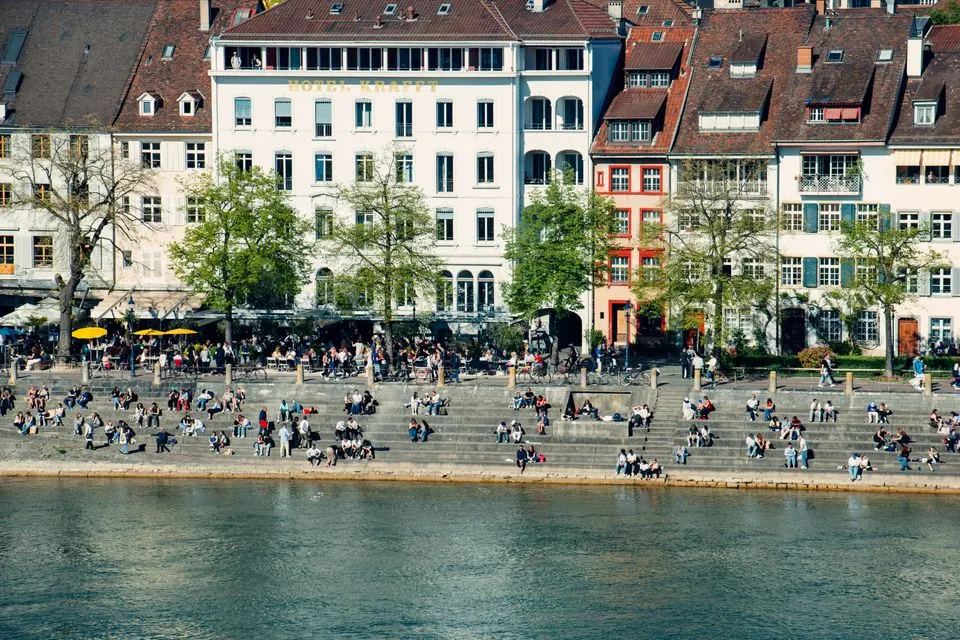 Hotel Märthof — People relax and socialize by the Rhine River in Basel, showcasing vibrant city life.