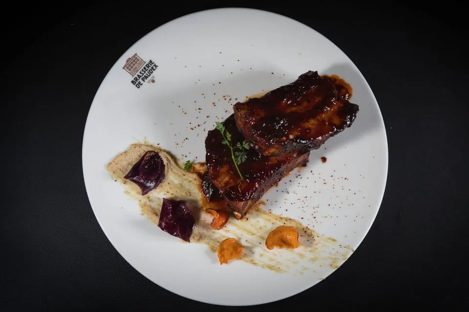 La Table de Valrose — Close-up of BBQ ribs with gourmet garnishing on a white plate.