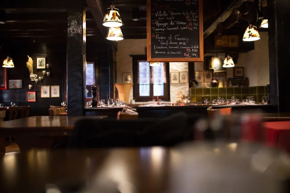 La Table de Valrose — Warm and inviting interior design of a vintage-style restaurant with wooden furnishings and dim lighting.