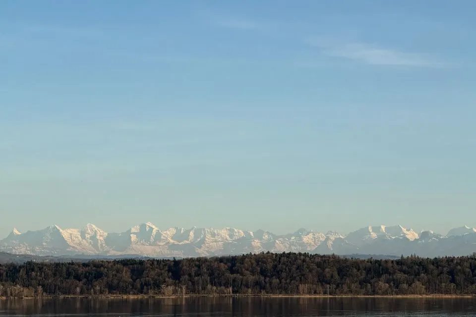 Tranquil landscape of Swiss Alps viewed across Lake Murten, capturing serene natural beauty in Switzerland.