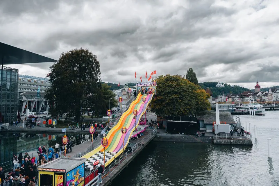 Lucerne Carnival — Vibrant carnival slide on a lakeside pier in Lucerne, Switzerland, with a lively atmosphere.