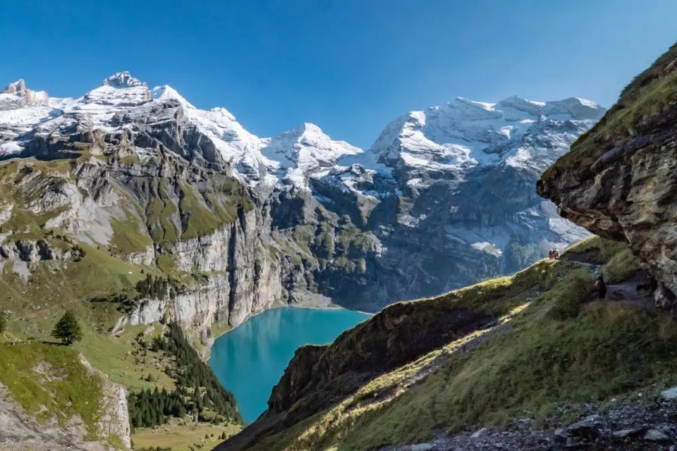 No. 9 Lakes Route — Scenic view of Oeschinen Lake with snow-capped Swiss Alps under blue sky.