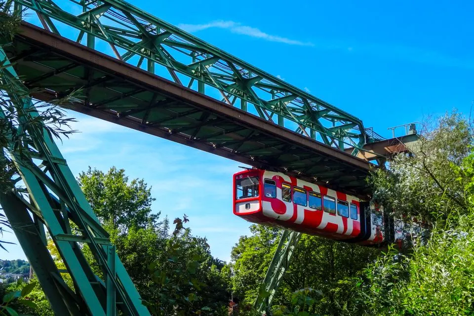 Saentis-Schwebebahn — Explore the scenic Wuppertal Suspension Railway amidst lush greenery and a clear blue sky.