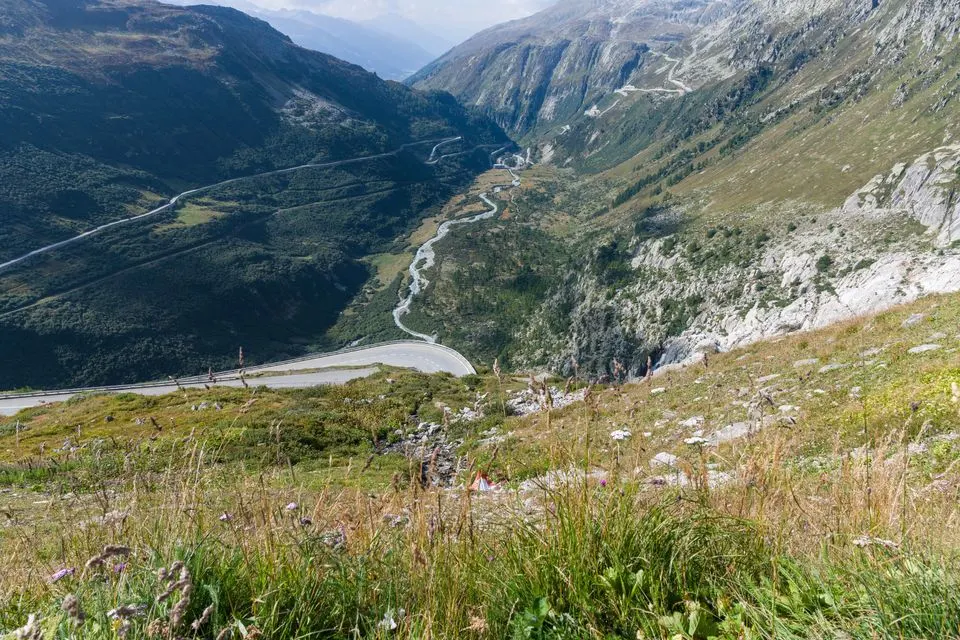 Simplon Pass — Beautiful panoramic view of the Swiss Alps with winding roads and lush valleys under a clear sky.