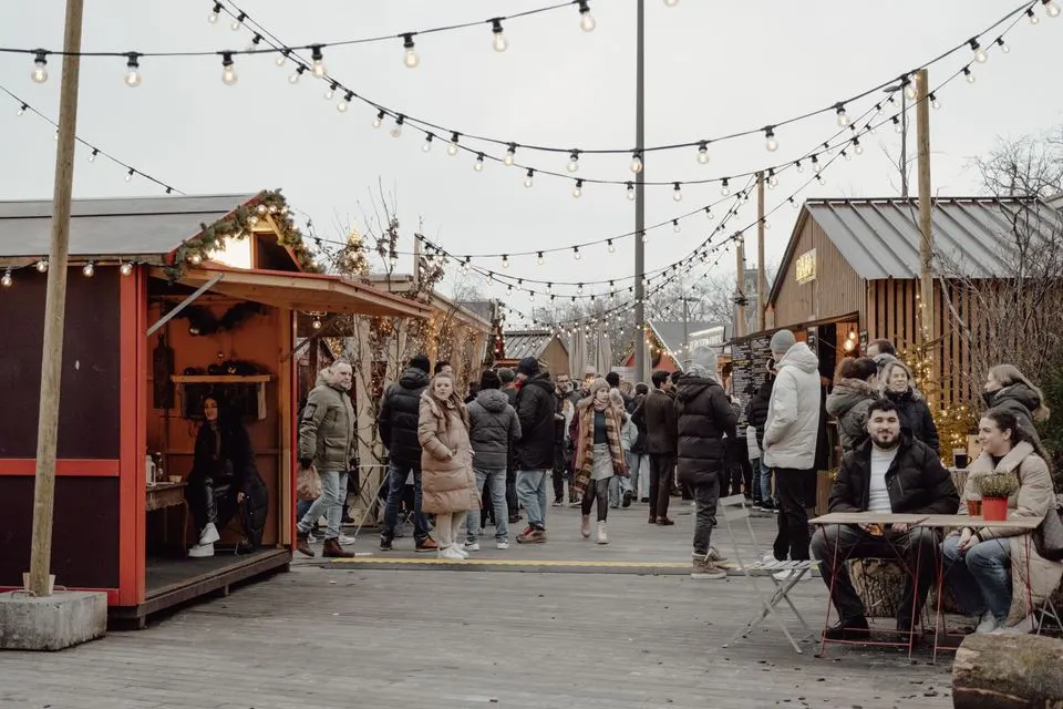 St. Gallen Christmas Market — Festive winter market in Zurich with people enjoying food and shopping under string lights.