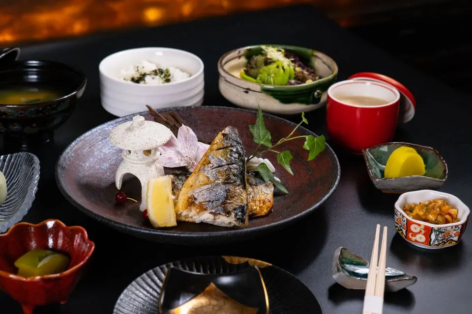 The Japanese Restaurant — Authentic Japanese dining setup featuring grilled fish and various side dishes in a restaurant setting.