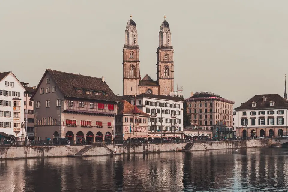Capture of Zürich's historic Grossmünster Cathedral and riverside architecture reflecting on the water.